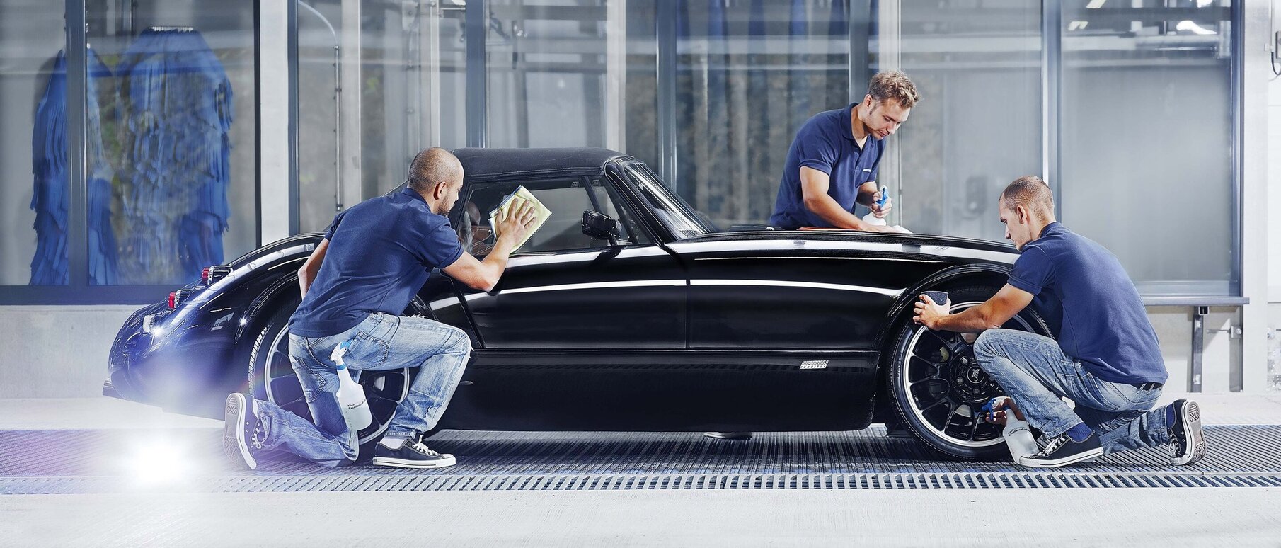 Employees clean a luxury car by hand in the car wash